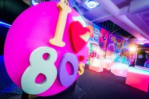 I heart 80's sign in bright colours with light up chairs in background