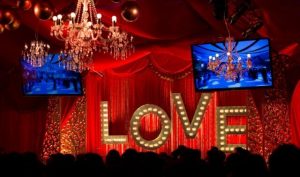 Red draping curtains and LOVE light up sign and hanging chandeliers