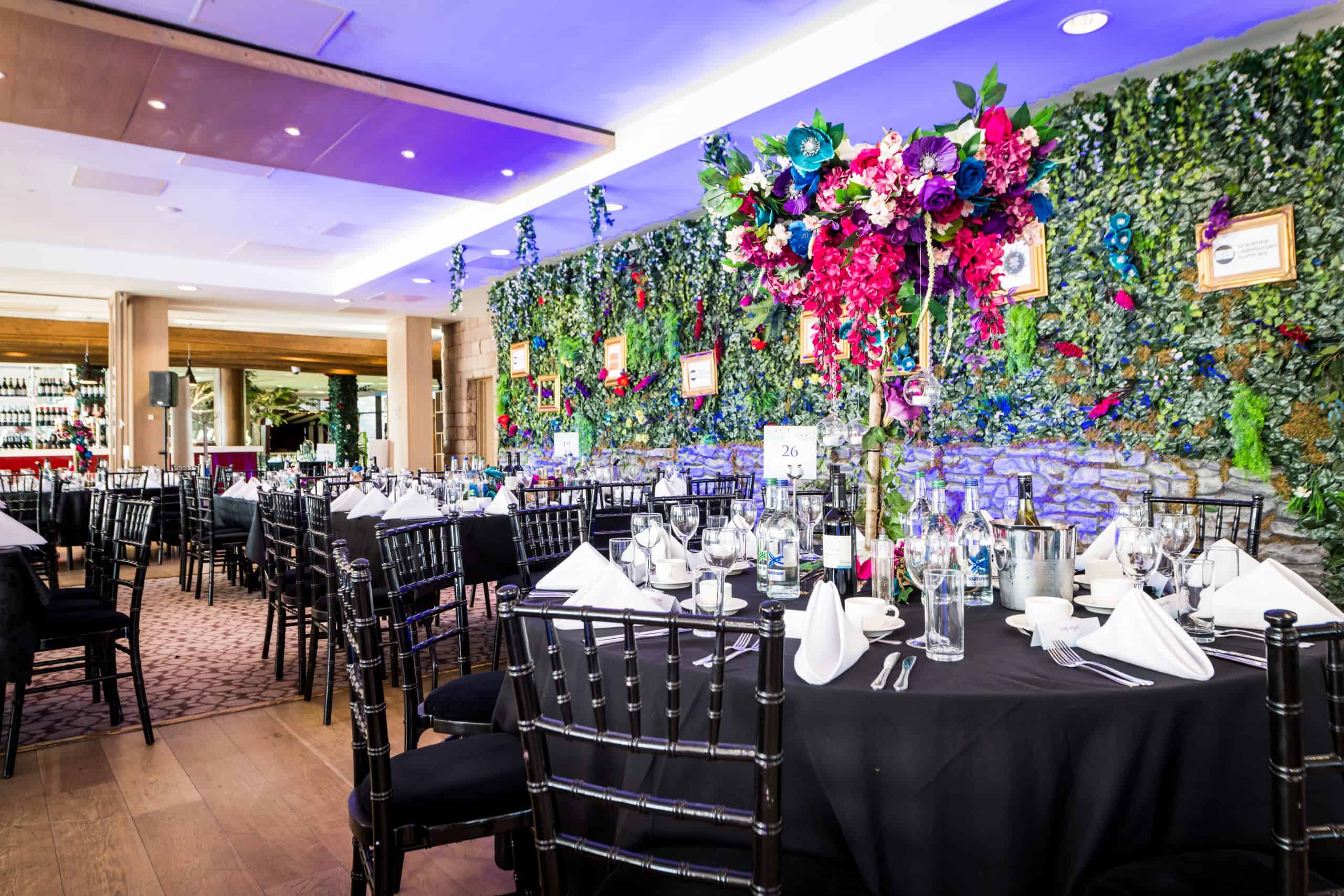 Foliage and flower wall with floral table centres with black table cloth