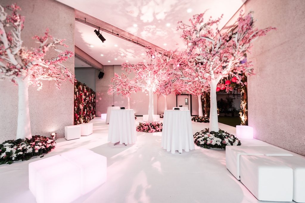 Summer Theme cherry blossom trees fresh clean new summer growth white cube seating white peosur tables foliage wall