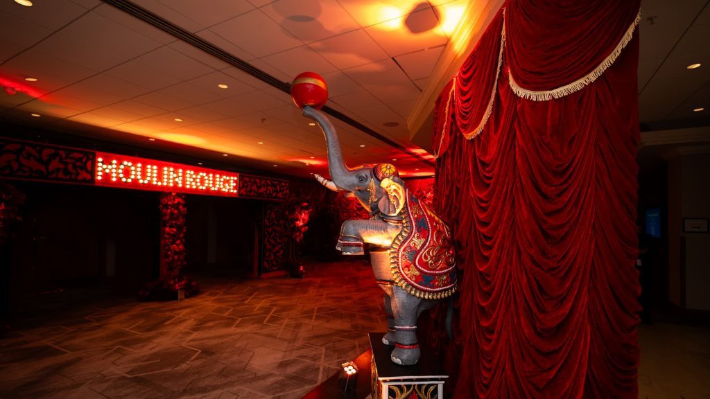 Eventologists Moulin Rouge Entranceway with elephant, illuminated sign and red drapings